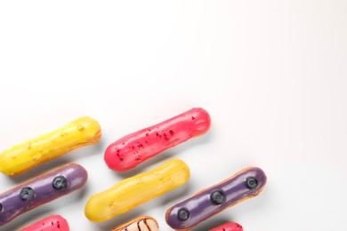 Photo of Delicious eclairs covered with glaze on white background, top view