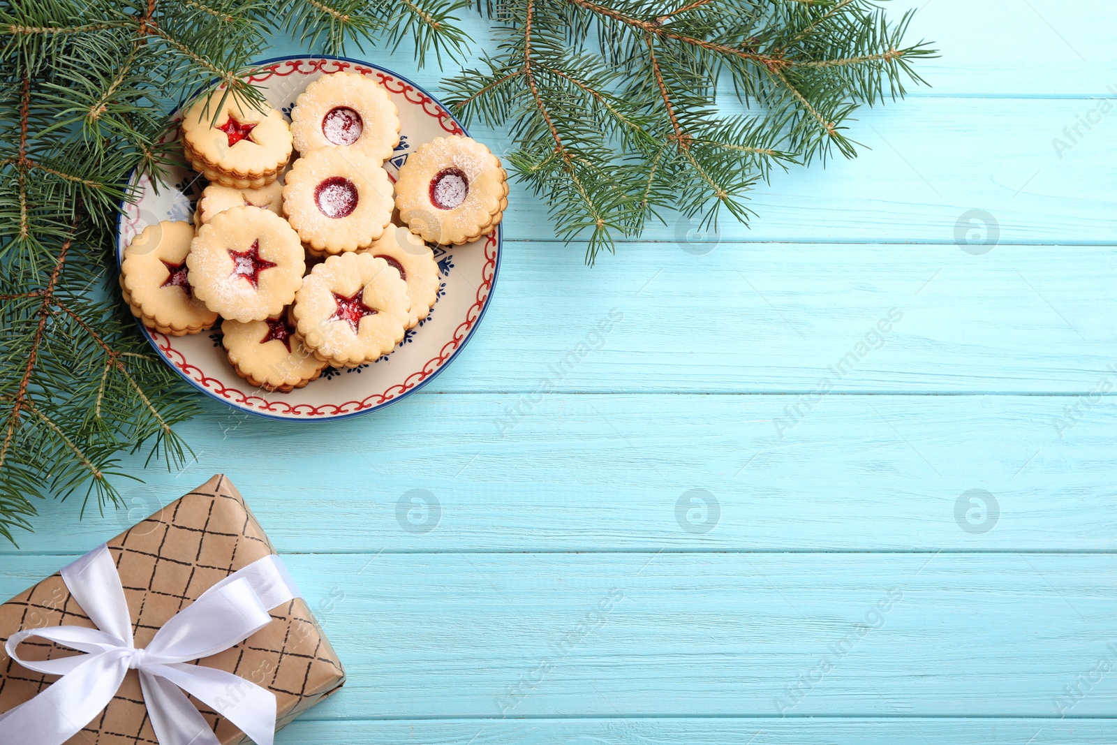 Photo of Traditional Christmas Linzer cookies with sweet jam, gift box and fir branches on wooden background