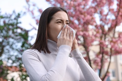 Woman with napkin suffering from seasonal allergy on spring day