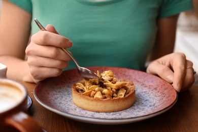 Photo of Woman eating delicious cake at table, closeup