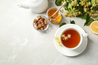 Photo of Flat lay composition with tasty tea and linden blossom on light grey marble table. Space for text