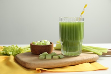 Glass of delicious celery juice and vegetables on white table