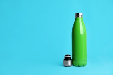 Photo of Stylish thermo bottle on light blue background, space for text