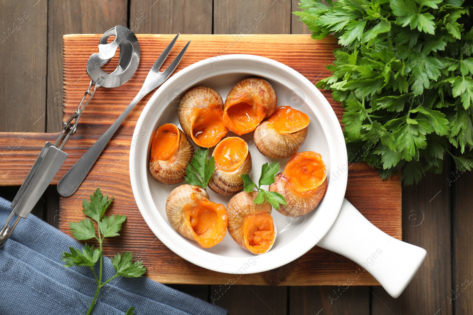 Photo of Delicious cooked snails served on wooden table, flat lay