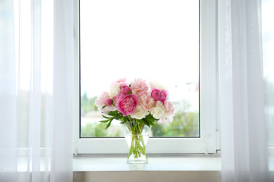 Photo of Beautiful peony bouquet in vase on windowsill indoors. Space for text