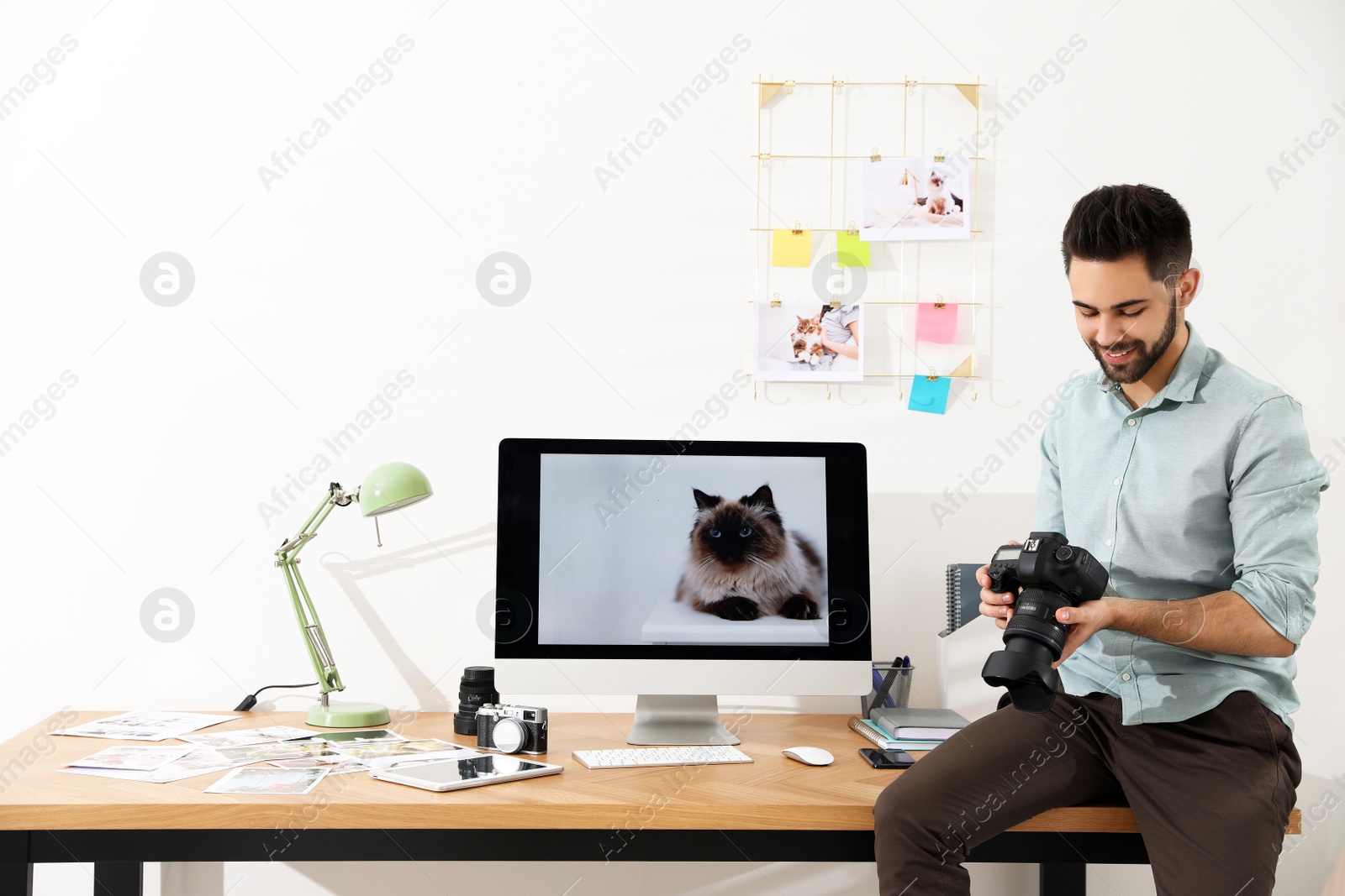 Photo of Professional photographer with camera working in light modern office