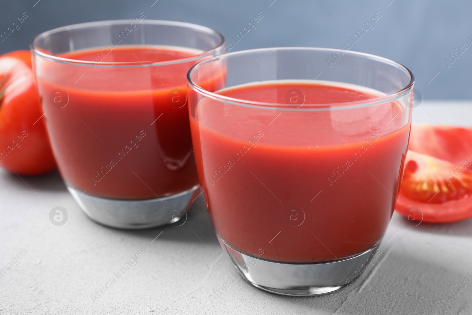 Photo of Delicious fresh tomato juice on light grey table, closeup