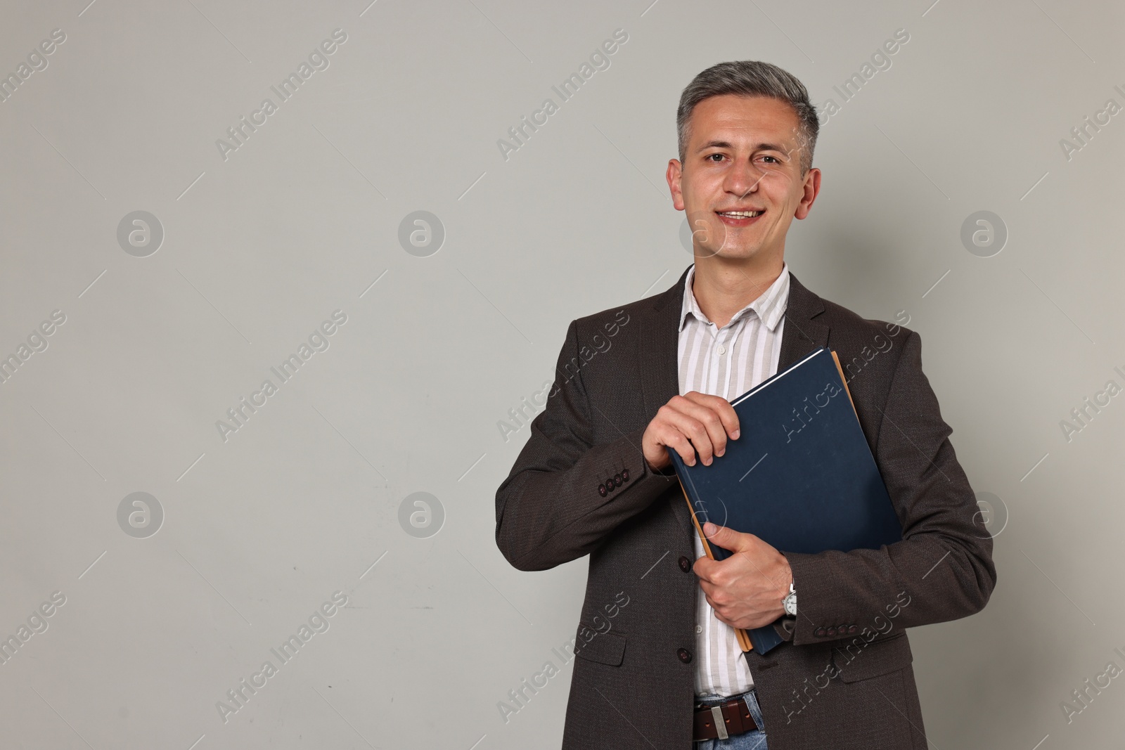 Photo of Happy teacher with notebooks on grey background, space for text