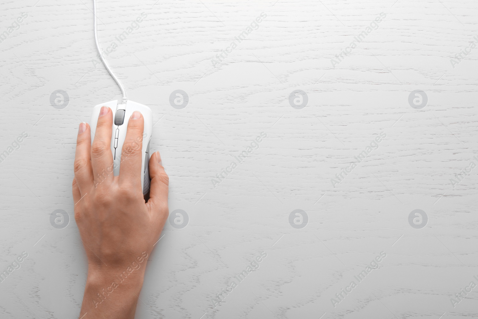 Photo of Woman using computer mouse on wooden background, top view. Space for text