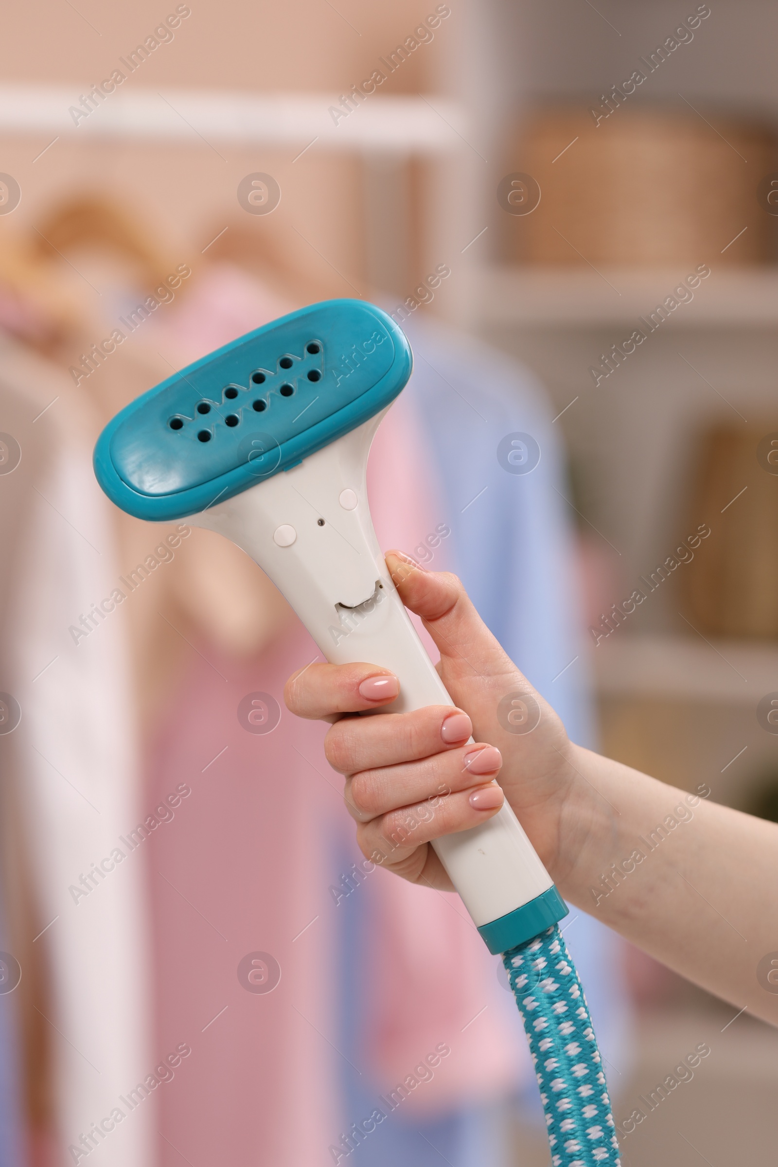 Photo of Woman with modern steam iron at home, closeup