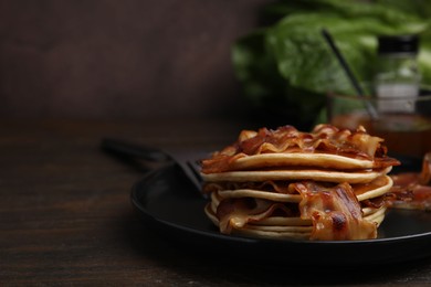 Delicious pancakes with fried bacon served on wooden table, closeup. Space for text