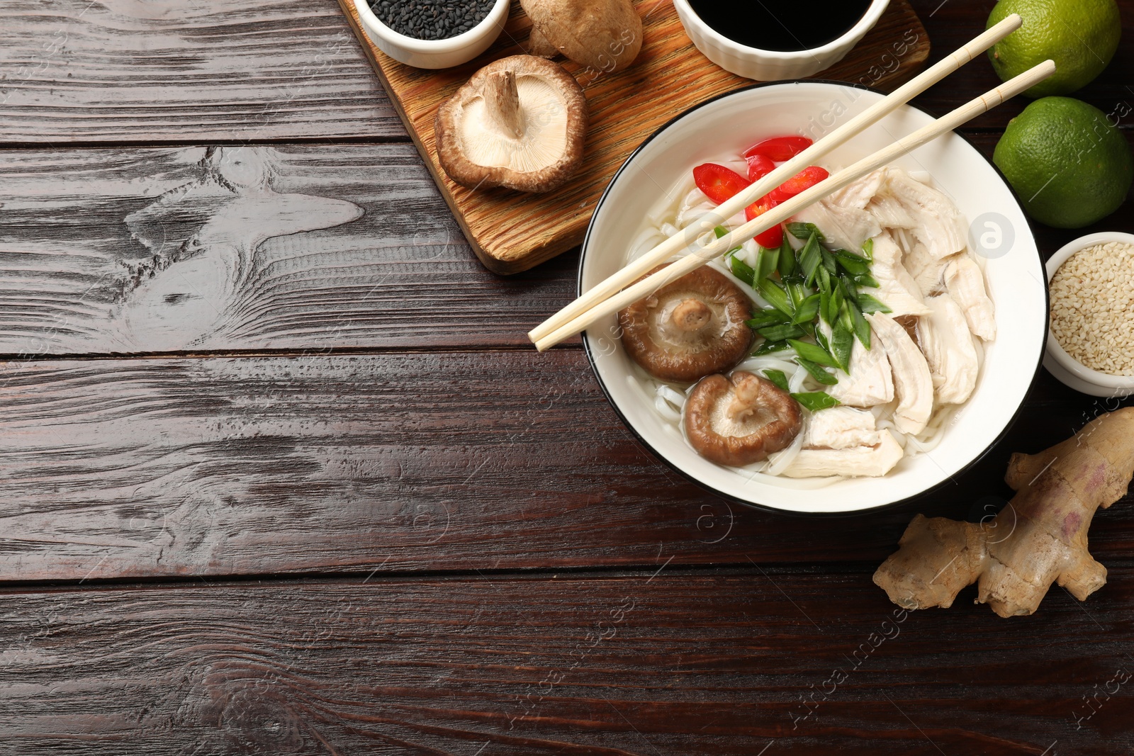 Photo of Delicious ramen with meat and ingredients on wooden table, flat lay. Space for text