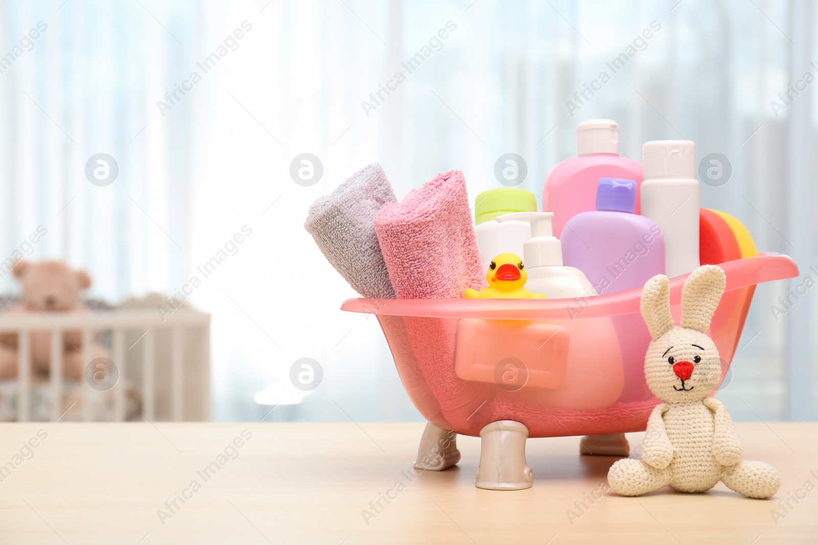 Photo of Baby cosmetic products, toys and towels on table indoors. Space for text