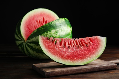 Photo of Yummy watermelon on wooden table against black background