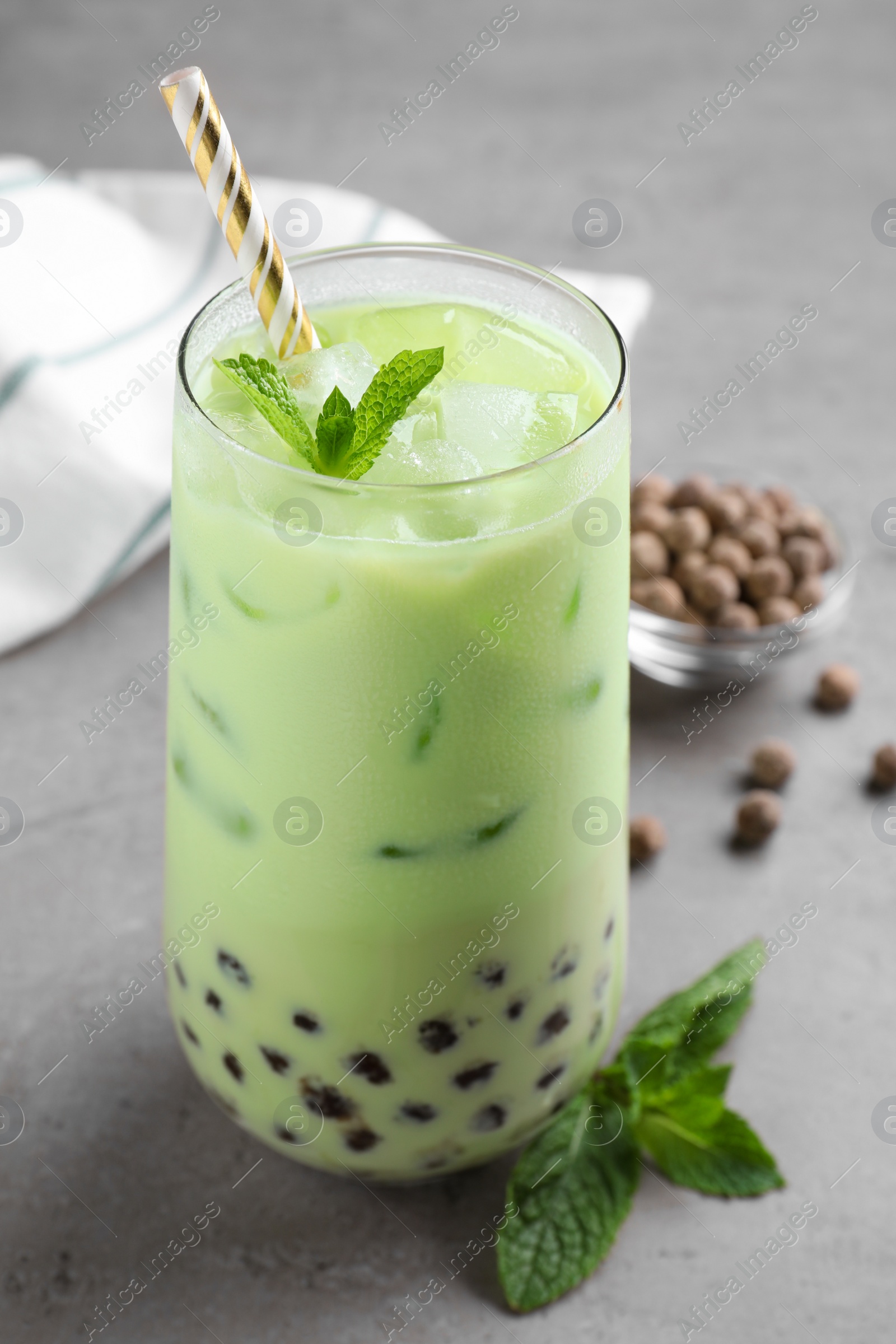 Photo of Tasty milk bubble tea with mint on light grey table, closeup