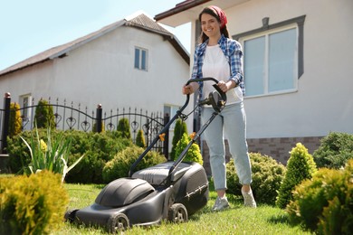 Woman cutting green grass with lawn mower in garden