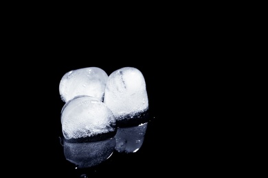 Photo of Melting ice cubes on black background. Space for text