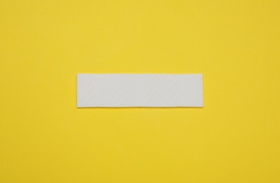 Photo of Stick of tasty chewing gum on yellow background, top view