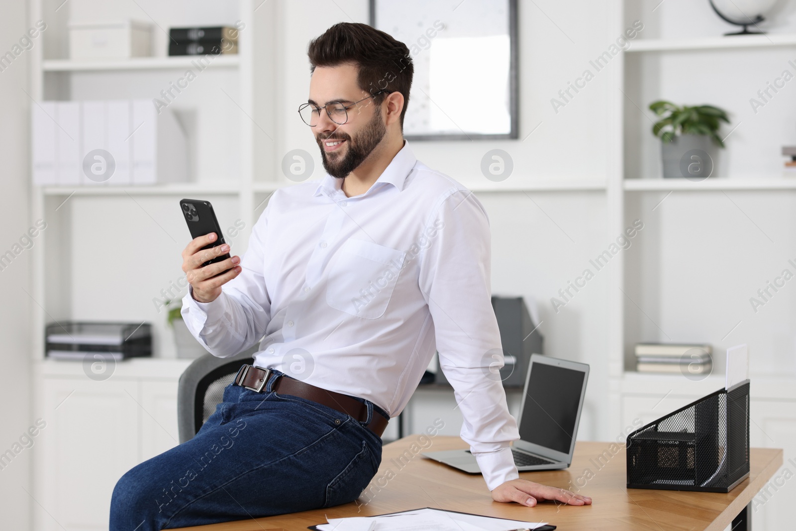 Photo of Handsome young man using smartphone in office