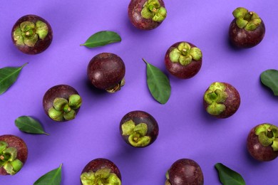 Fresh ripe mangosteen fruits with green leaves on violet background, flat lay