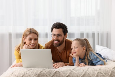 Photo of Happy family with laptop on bed at home