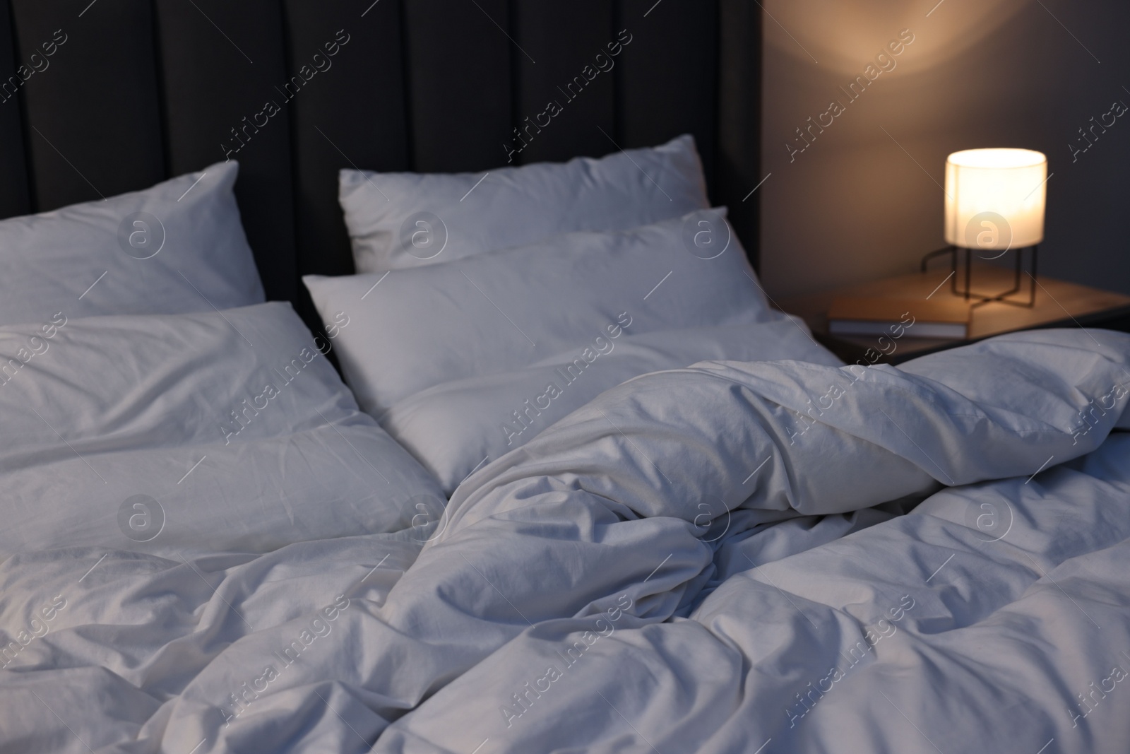 Photo of Soft bed and bedside table with nightlight indoors