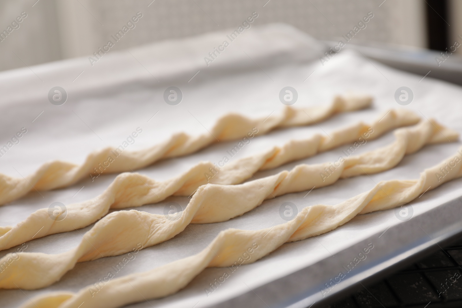 Photo of Homemade breadsticks on baking sheet, closeup. Cooking traditional grissini