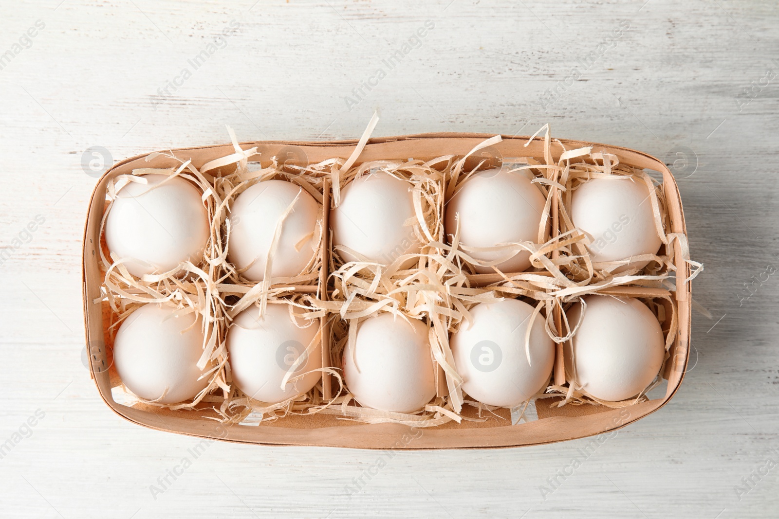 Photo of Basket with raw chicken eggs on wooden background, top view