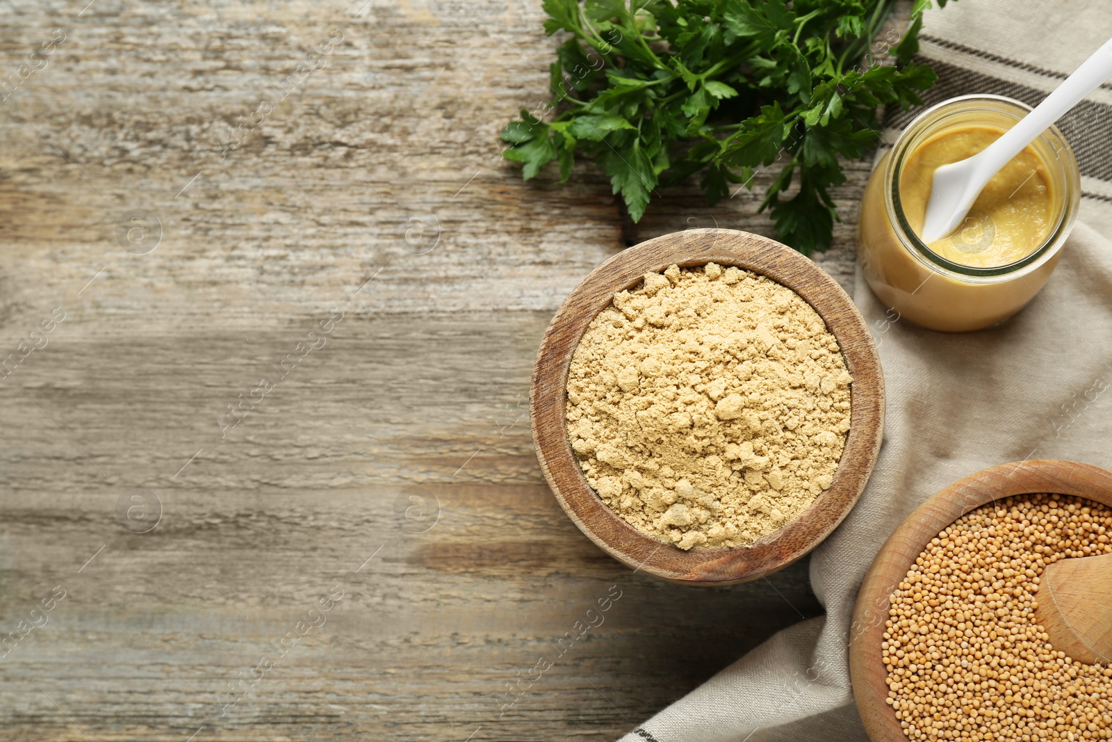 Photo of Flat lay composition with mustard powder, seeds and parsley on wooden table. Space for text