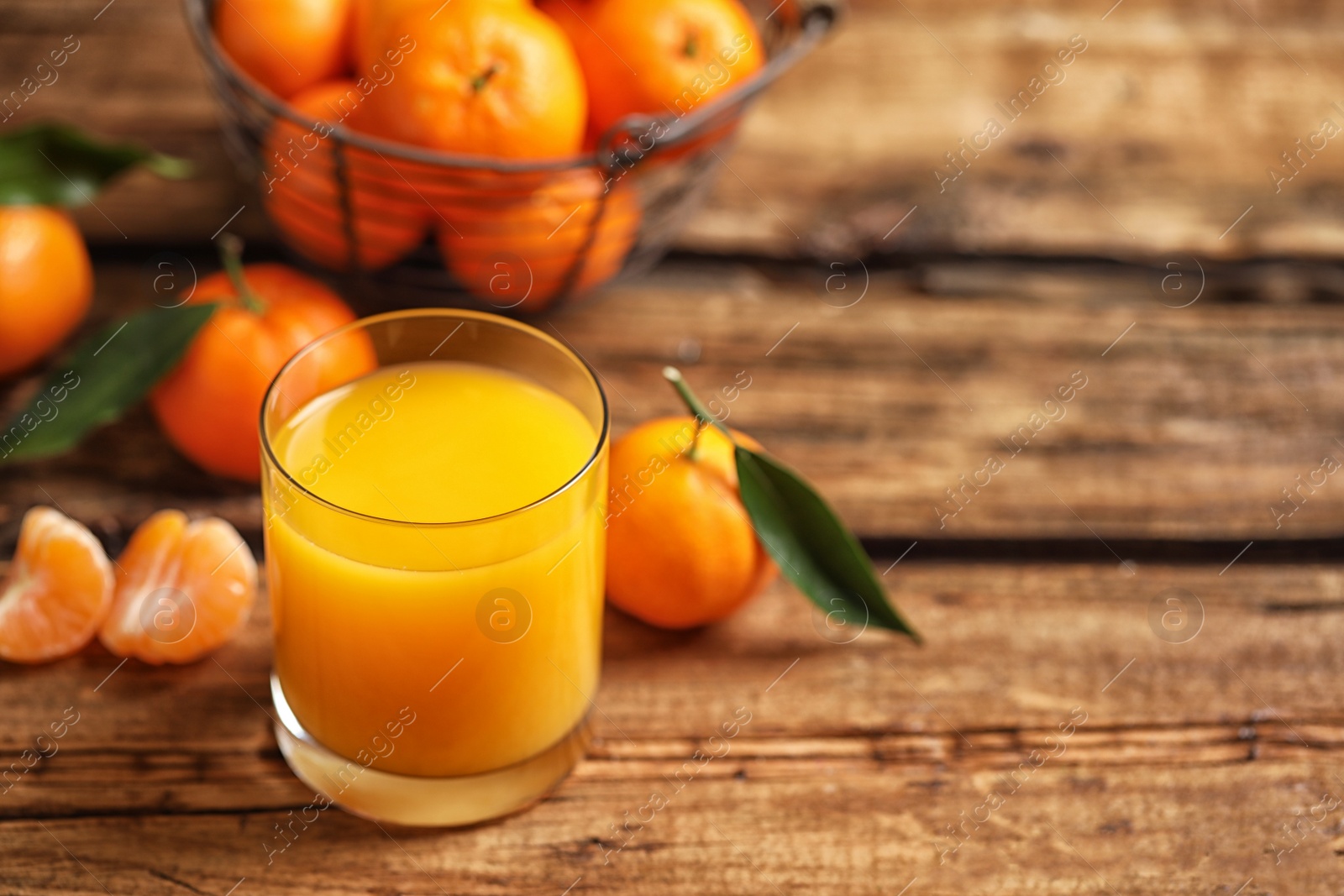 Photo of Glass of fresh tangerine juice and fruits on wooden table. Space for text