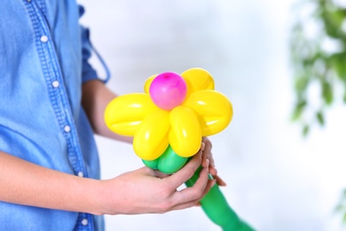 Woman making balloon figure on blurred background, closeup