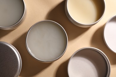 Photo of Different lip balms on beige background, flat lay