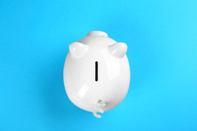 Photo of White piggy bank on blue background, top view