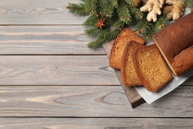 Photo of Delicious gingerbread cake, ingredients and fir branches on wooden table, flat lay. Space for text