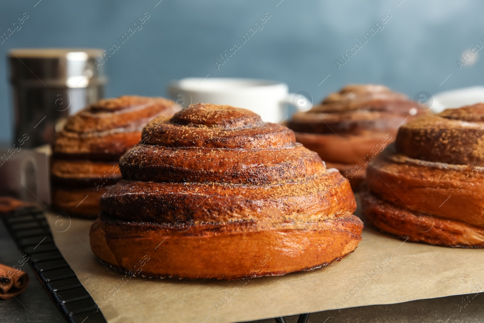 Photo of Cooling rack with freshly baked cinnamon rolls on table, closeup