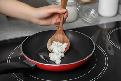 Woman cooking with coconut oil on induction stove, closeup