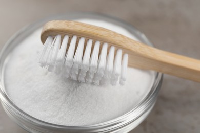 Photo of Bamboo toothbrush and bowl of baking soda on table, closeup