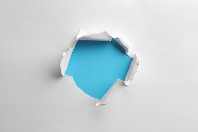 Photo of Hole in white paper on light blue background