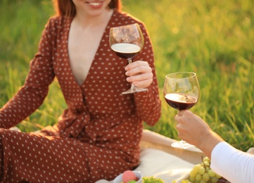 Young couple with wine having picnic in green park, closeup