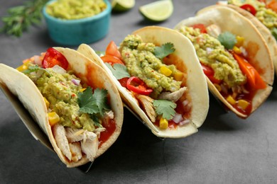 Photo of Delicious tacos with guacamole, meat and vegetables on grey table, closeup