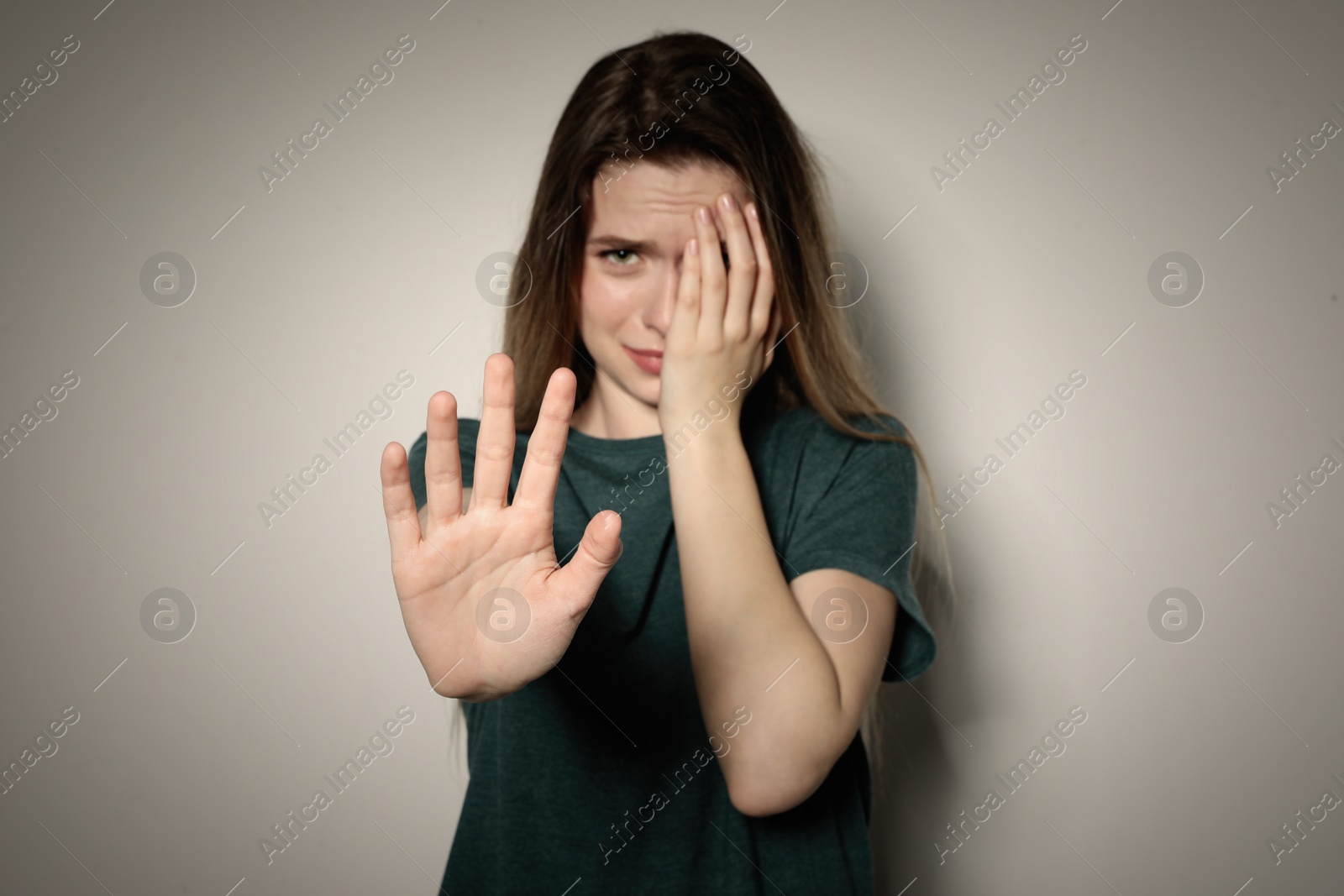 Photo of Young woman making stop gesture against light background, focus on hand