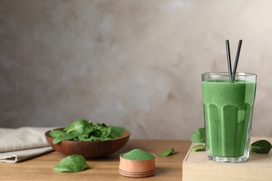 Composition with spirulina smoothie, powder and spinach on table. Space for text