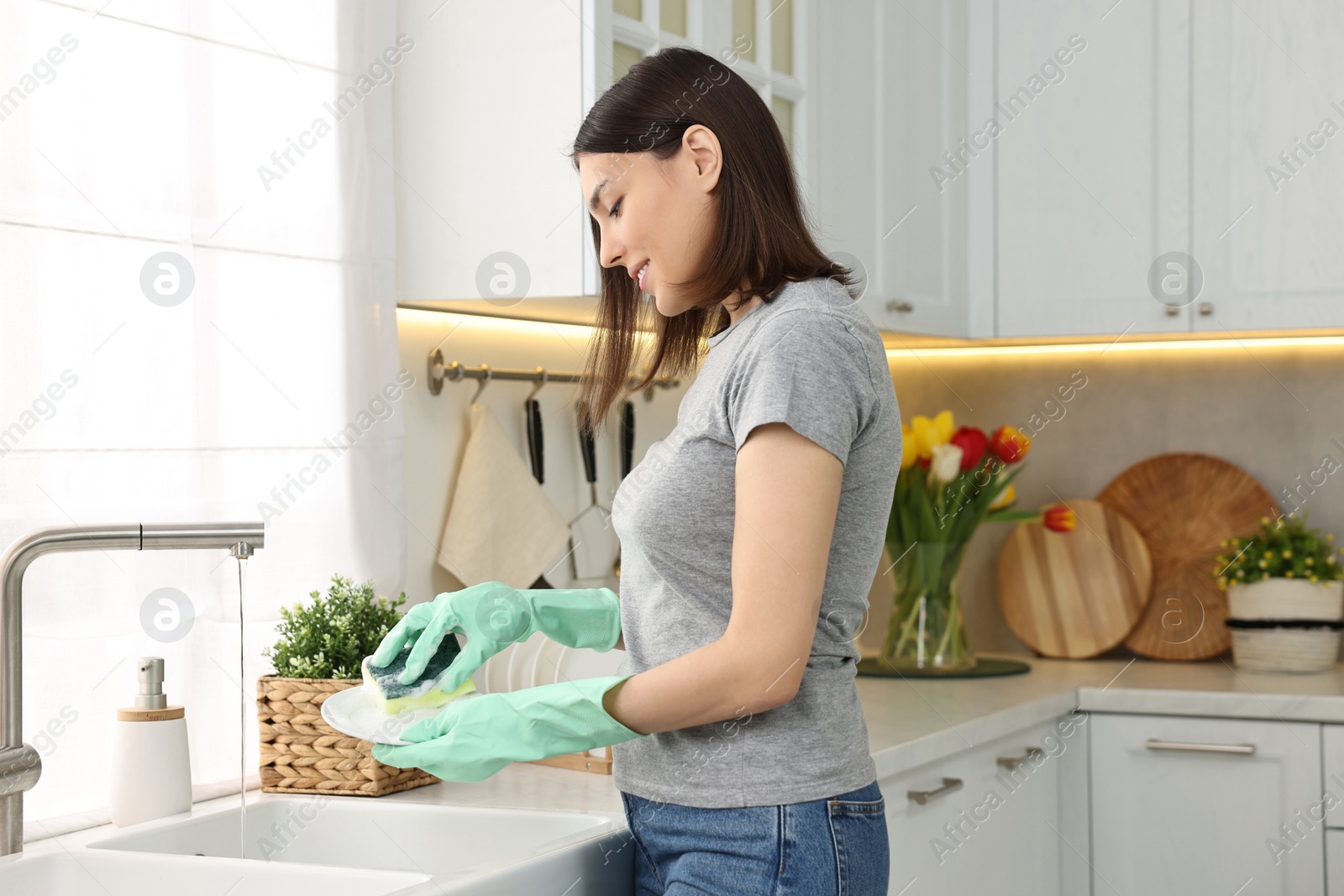 Photo of Woman washing dishes in kitchen sink. Cleaning chores