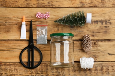 Photo of Set of instruments and materials for snow globe on wooden table, flat lay