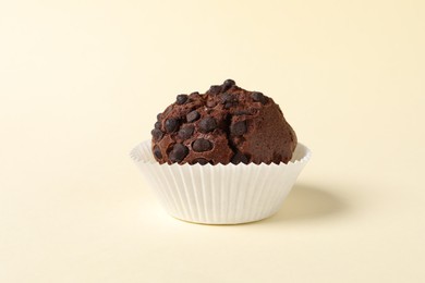 Photo of One tasty chocolate muffin on beige background