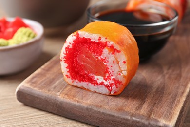 Photo of Delicious sushi roll with salmon and tobiko on wooden table, closeup