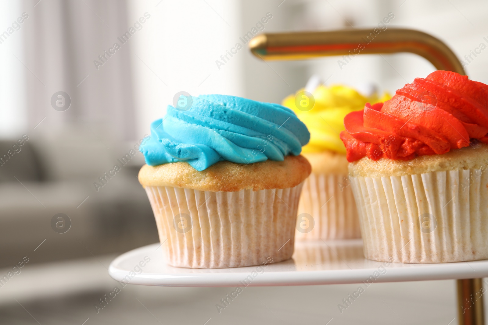 Photo of Delicious cupcakes with bright cream on dessert stand indoors, closeup