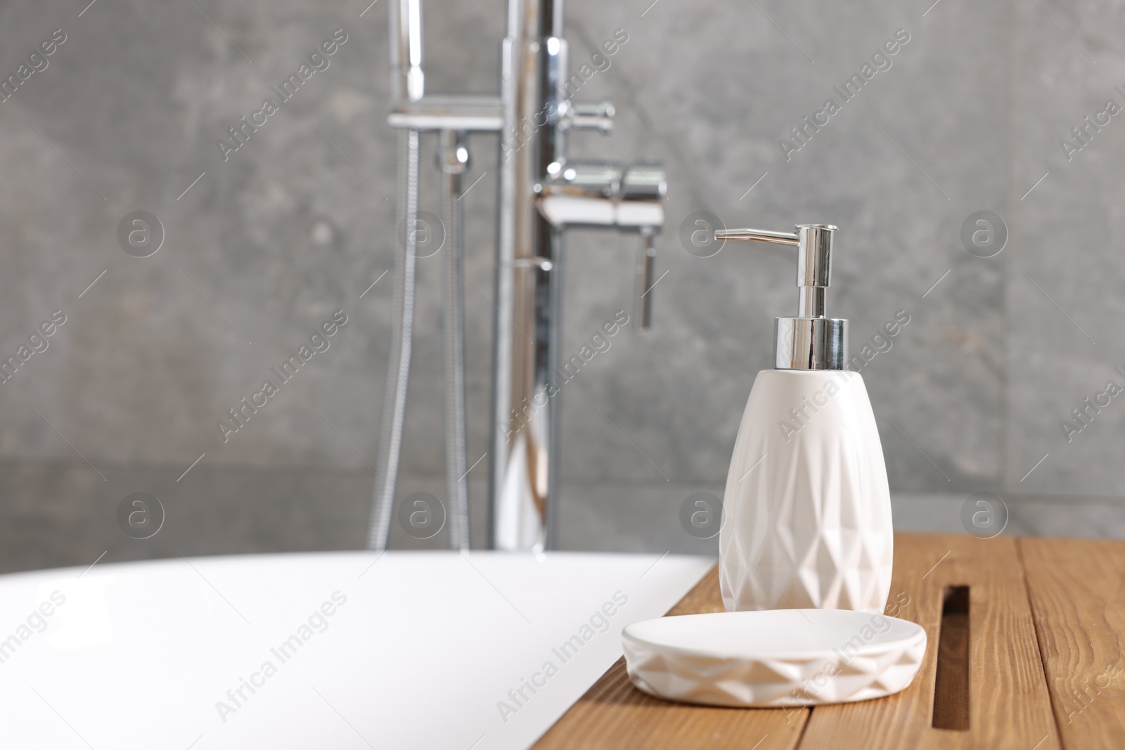 Photo of Bath accessories. Dispenser and soap dish on tub in bathroom, space for text