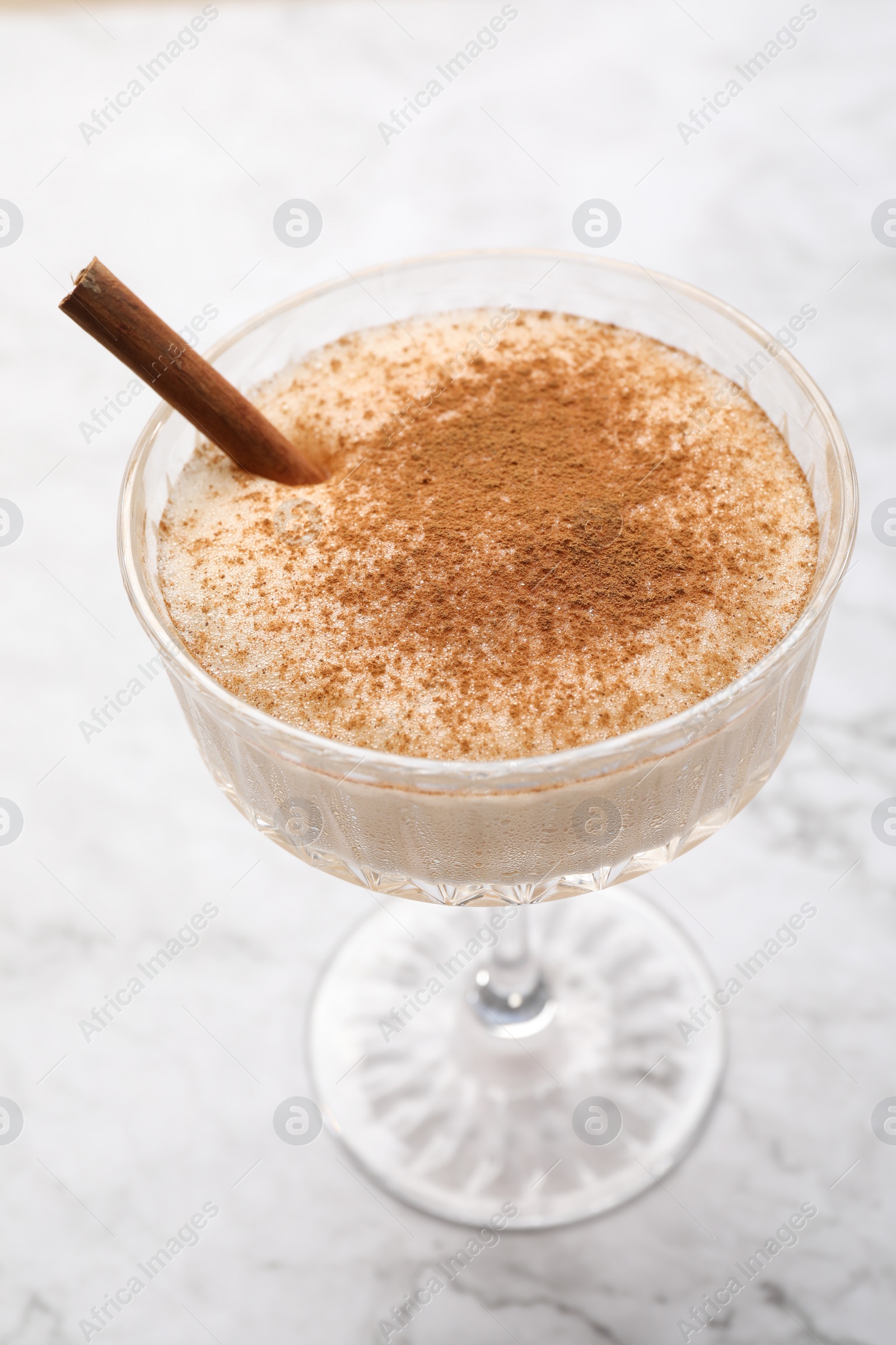 Photo of Delicious eggnog with cinnamon on white marble table