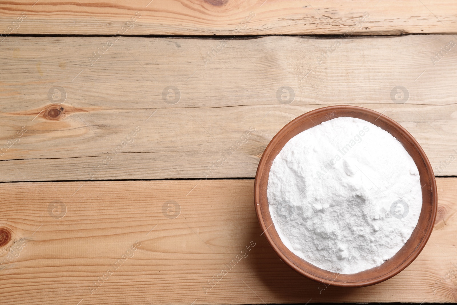 Photo of Bowl with baking soda on wooden table, top view